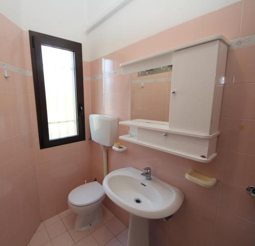 a bathroom with a sink and a toilet and a window at Villa Gloria appartamento D02 in Rosolina Mare