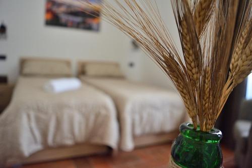 a bedroom with two beds and a green vase with grass at La Gravina in Gravina in Puglia