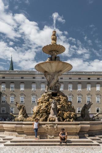 two people standing in front of a fountain in front of a building at Landgasthof Reitsamerhof in Werfen