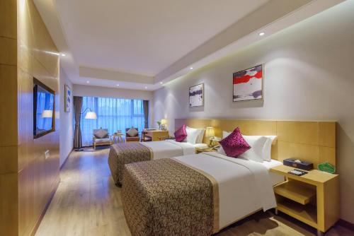 重慶市にあるNovo Hotel Chongqingのベッド2台とリビングルームが備わるホテルルームです。