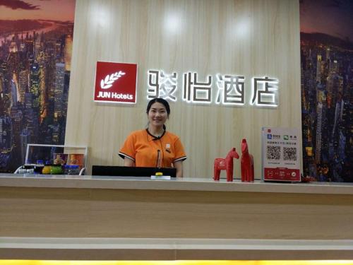 a woman standing behind a counter in a store at JUN Hotels Shandong Zaohuang Tengzhou Jinghe West Road in Tengzhou