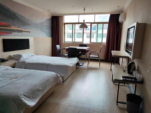 a hotel room with two beds and a television at JUN Hotels Nanchang Honggutan New District Cuiyuan Road Subway Station in Nanchang