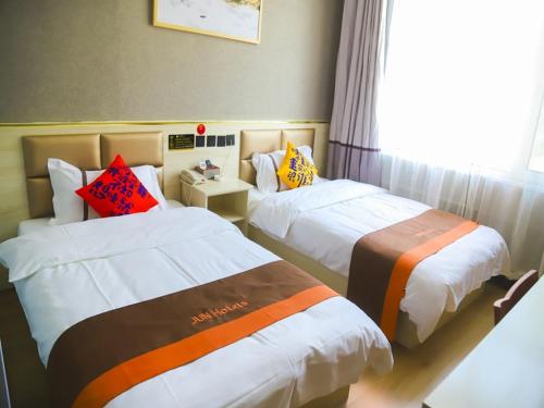 a hotel room with two beds and a window at JUN Hotels Shandong Ji'nan Zhangqiu Diao Town Chemical Industrial Park 