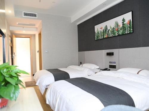 two beds in a bedroom with a tv on the wall at Thank Inn Chain Hotel Shanxi Jinzhong Yuci District Yunhua Street in Jinzhong
