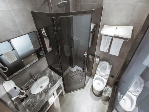 a bathroom with a shower and a toilet and a sink at JUN Hotels Jiangsu Wuxi East Railway Station Store in Zhaqiao