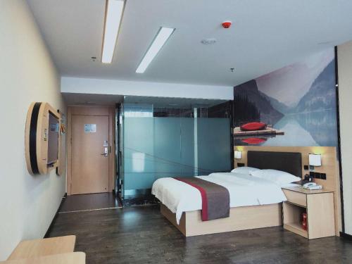 1 dormitorio con 1 cama y una pintura en la pared en Thank Inn Chain Hotel Jiangmen Kaiping Shuikou Passenger Transport Station, en Jiangmen