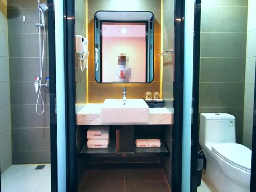 a bathroom with a sink and a mirror and a toilet at Thank Inn Plus Hotel Jining Qufu Confucius Museum in Jining