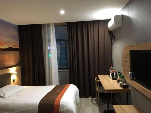 Habitación de hotel con cama, mesa y TV en JUN Hotels Anhui Fuyang Yingshang County Guanzhong Avenue Store, en Fuyang