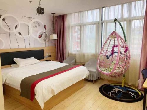 ein Schlafzimmer mit einem Bett und einer hängenden Schaukel in der Unterkunft Thank Inn Chain Hotel Jiangxi Ganzhou Yudu County Railway Station Store in Ganzhou