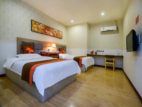 a hotel room with two beds and a television at JUN Hotels Chongqing Nan'an Nanping Dongmo in Chongqing