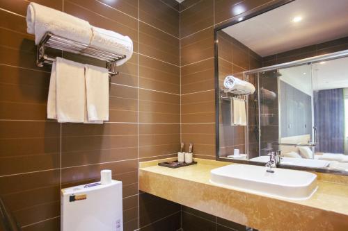 a bathroom with a sink and a mirror at JUN Hotels Langfang Guangyang District Wanda Plaza in Langfang