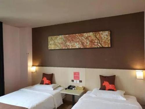 a hotel room with two beds and a painting on the wall at JUN Hotels Jiangsu Suzhou Kunshan Lujia Town Tongjin Road in Kunshan
