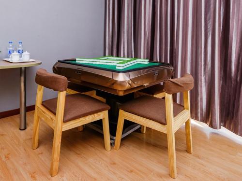 a table with a suitcase on it with two chairs at JUN Hotels Chongqing Nan'an Nanping Dongmo in Chongqing