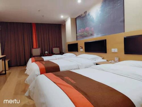 a group of four beds in a hotel room at JUN Hotels Hunan Zhuzhou Lusong District Central Plaza in Zhuzhou