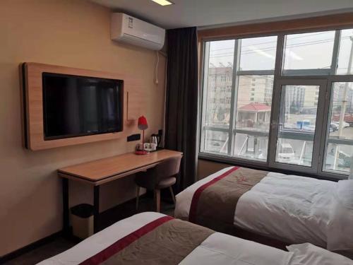 a hotel room with a desk with a television and a bed at Thank Inn Chain Hotel Shanxi Changzhi Huguan County Bus Station Store in Changzhi