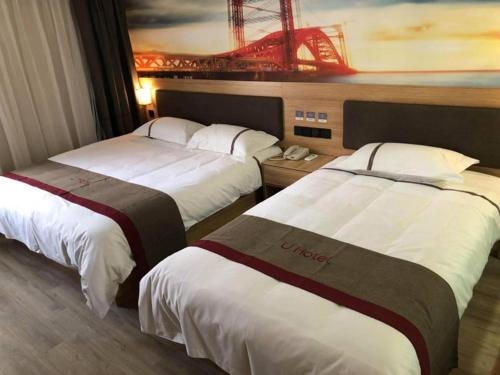 two beds in a hotel room with a painting on the wall at Thank Inn Chain Hotel Jiangsu Xuzhou Suining County Renmin West Road Store in Xuzhou