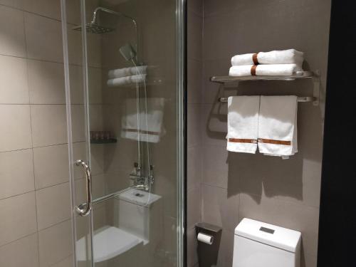 a bathroom with a shower and a toilet and towels at Up And In Ganzhou Zhanggong District Baoneng City in Ganzhou