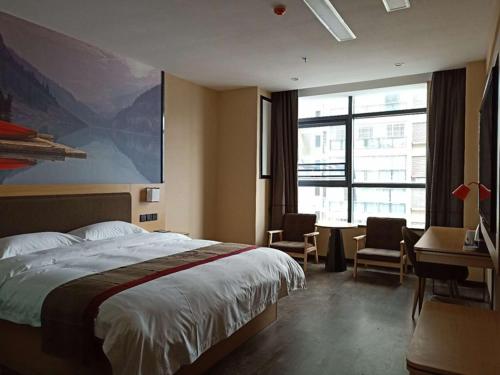 ein Hotelzimmer mit einem Bett, einem Schreibtisch und einem Fenster in der Unterkunft Thank Inn Plus Hotel Guizhou Zunyi Suiyang County Shixiang Avenue in Zunyi