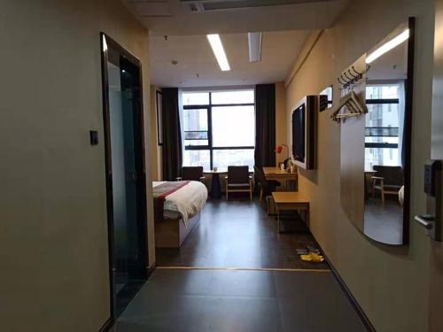 ein Hotelzimmer mit einem Bett, einem Schreibtisch und einem Spiegel in der Unterkunft Thank Inn Plus Hotel Guizhou Zunyi Suiyang County Shixiang Avenue in Zunyi