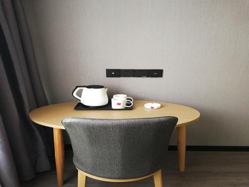 a table with a tea kettle and two cups on it at Thank Inn Chain Hotel Yangzhou Hanjiang District Chahe University Town in Yangzhou