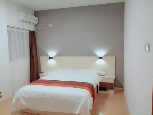 sypialnia z białym łóżkiem i 2 szafkami nocnymi w obiekcie JUN Hotels Anhui Huangshan Tunxi District Huangshan Old Street w mieście Huang Shan