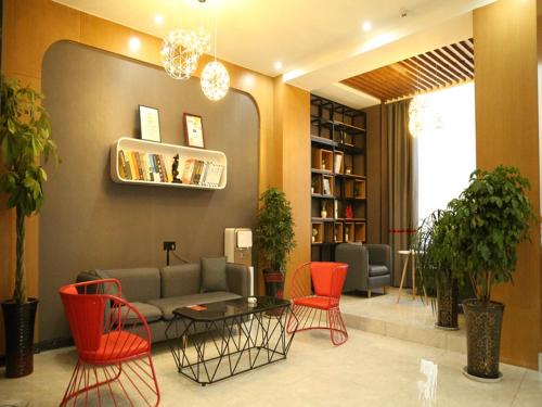 a living room with a couch and red chairs at Thank Inn Chain Hotel Xinyang Gushi County Hongsu Avenue 