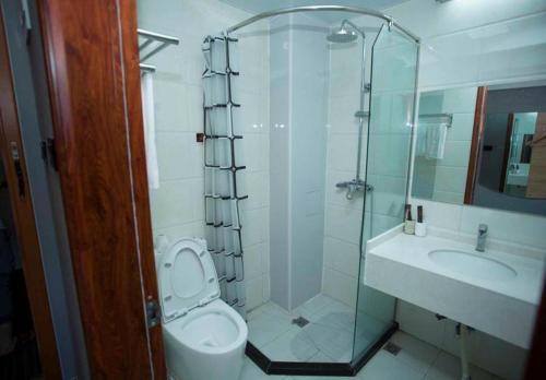 a bathroom with a shower and a toilet and a sink at JUN Hotels Shandong Weihai Huancui District High Speed Rail North Station Store in Weihai