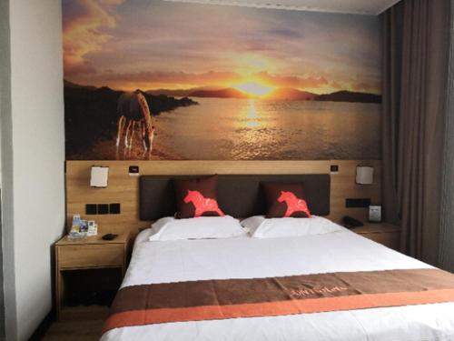 a bedroom with a bed with a painting on the wall at JUN Hotels Anhui Bangbu Guzhen County Huihe Road Store in Qiaokou