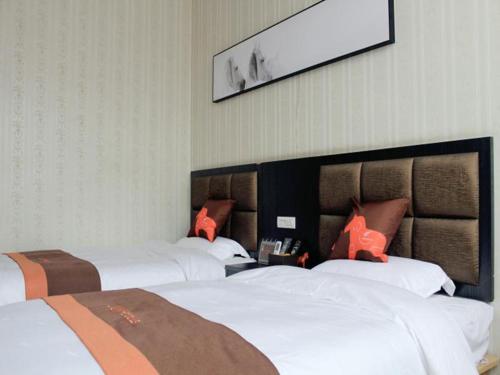 um quarto de hotel com três camas e uma foto na parede em JUN Hotels He'nan Zhoukou Shenqiu Zhaofeng Avenue em Zhoukou