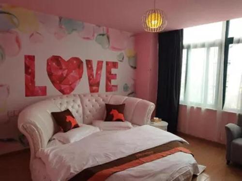 ein Schlafzimmer mit einem weißen Bett mit einem Liebesschild an der Wand in der Unterkunft JUN Hotels Jiangsu Suzhou Kunshan Lujia Town Tongjin Road in Kunshan