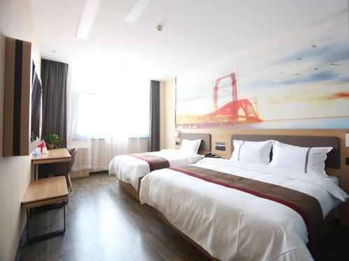 two beds in a hotel room with a painting on the wall at Thank Inn Plus Hotel Shijiazhuang Gaocheng District Century Avenue in Shijiazhuang