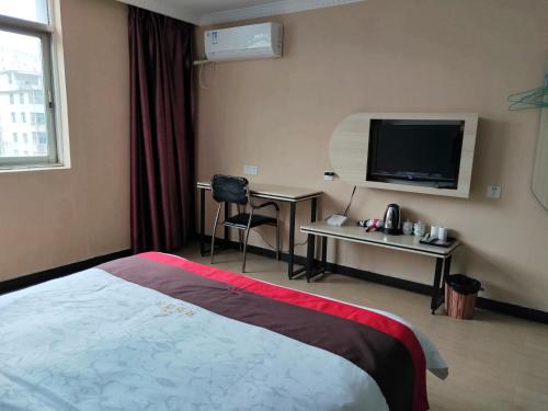 ein Hotelzimmer mit einem Bett und einem Flachbild-TV in der Unterkunft JUN Hotels Nanchang Honggutan New District Cuiyuan Road Subway Station in Nanchang