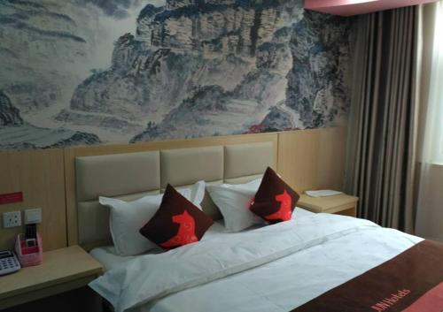 a bedroom with a large bed with red pillows at JUN Hotels Anyang Beiguan District Railway Station in Anyang