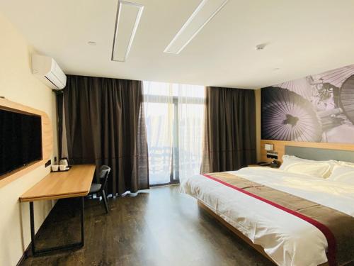 a hotel room with a large bed and a desk at Thank Inn Chain Hotel Jiangsu Suzhou High-tech Zone Majian Xintiandi in Suzhou
