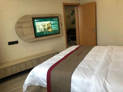 a bedroom with a bed with a television on the wall at Thank Inn Chain Hotel Liaocheng Yanggu County Fucheng in Liaocheng
