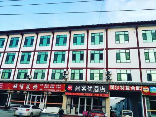 ein großes Gebäude mit Fenstern und davor geparkt in der Unterkunft Thank Inn Chain Hotel Shandong Linyi Linshu County Cangshan South Road in Linyi