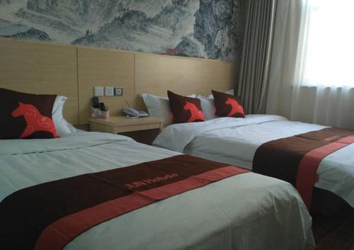 una camera d'albergo con due letti con cuscini a cavallo rosso di JUN Hotels Anyang Beiguan District Railway Station ad Anyang