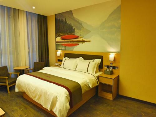 a hotel room with a bed and a painting on the wall at Thank Inn Chain Hotel Huaihua Tongdao Bus Station in Tongdao