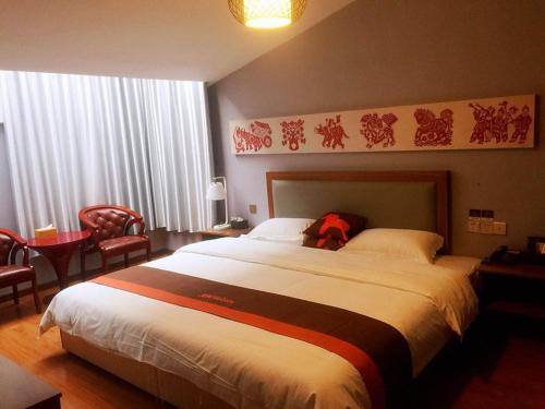 a bedroom with a large bed with a red backpack on it at JUN Hotels Jiangsu Taizhou Taixing Zhongnan Central City in Taixing