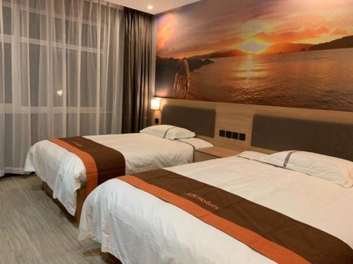 une chambre d'hôtel avec 2 lits et un tableau mural dans l'établissement JUN Hotels Hebei Baoding Rongcheng Banzheng North Street Store, à Baoding