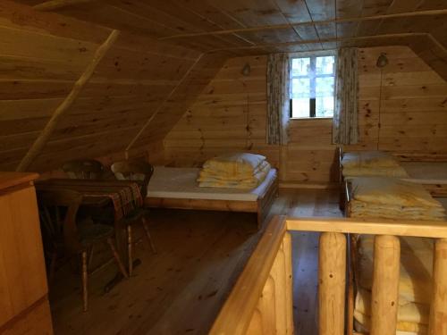 an attic room with two beds and a window at Mazurska Chatka in Zyzdrojowy Piecek