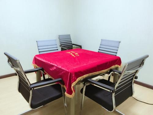 una mesa con cuatro sillas con un mantel rojo. en Thank Inn Chain Hotel Hubei Yidu Chengxiang, en Yidu