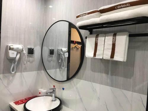 a bathroom with a mirror and a sink and towels at Thank Inn Chain Hotel Jiangxi Ganzhou Quannan County Shoumei Road in Quannan