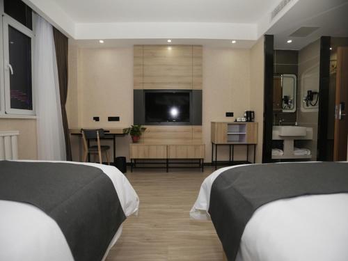 a hotel room with two beds and a flat screen tv at Up and In Hebei Hengshui Taocheng District Baoyun Avenue in Hengshui