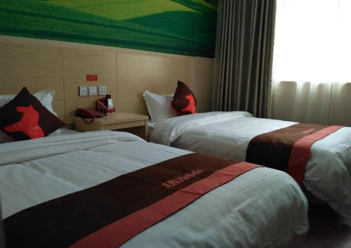 a hotel room with two beds and a window at JUN Hotels Anyang Beiguan District Railway Station in Anyang