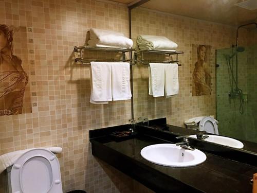 ein Badezimmer mit einem Waschbecken, einem WC und einem Spiegel in der Unterkunft JUN Hotels Chongqing Yubei District Jiangbei International Airport Airport Plaza in Yubei