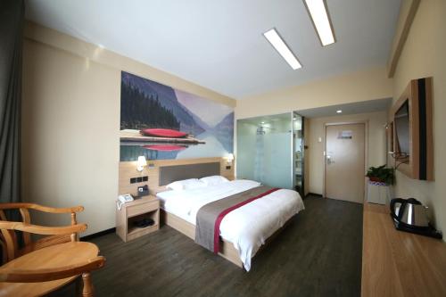 een hotelkamer met een groot bed en een stoel bij Thank Inn Chain Hotel Shandong Dezhou Lingcheng District Lingzhou Road Ginza in Dezhou