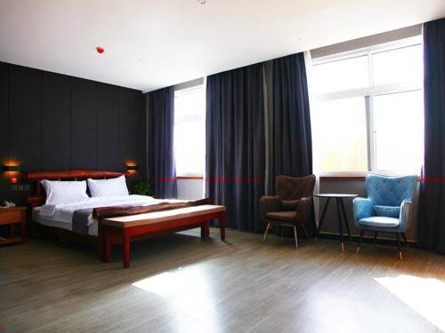 a hotel room with a bed and two chairs at JUN Hotels Hebei Hengshui Gucheng County Yingrui Plaza in Hengshui
