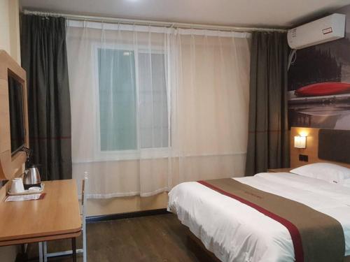 a bedroom with a bed and a desk and a window at Thank Inn Chain Hotel Shandong Dezhou Jiefang South Avenue Store in Dezhou