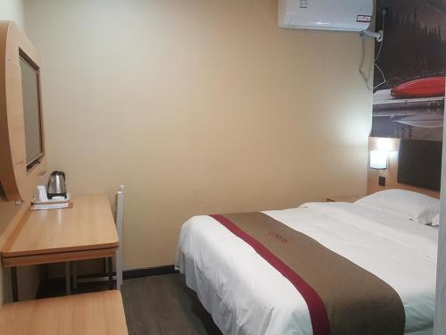 a hotel room with a bed and a wooden desk at Thank Inn Chain Hotel Shandong Dezhou Jiefang South Avenue Store in Dezhou